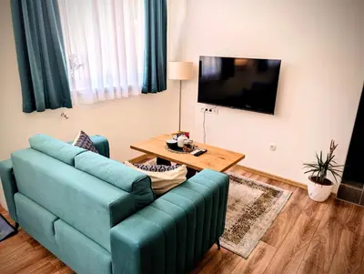 a living room with a blue couch and a table at Apartmani Dinarika in Livno