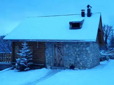 a cabin with a snow covered roof with a christmas tree at Kuća za odmor Vidikovac in Rumboci