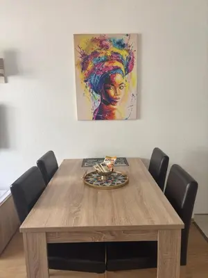 a wooden table with chairs and a painting on the wall at Apartman Urbana Oaza in Banja Luka