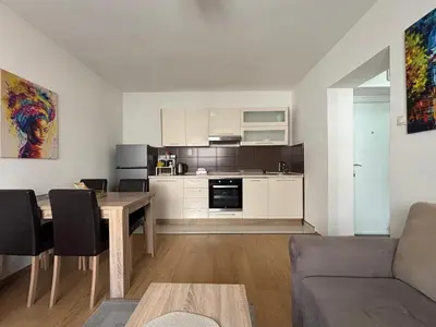 a living room with a table and a kitchen at Apartman Urbana Oaza in Banja Luka