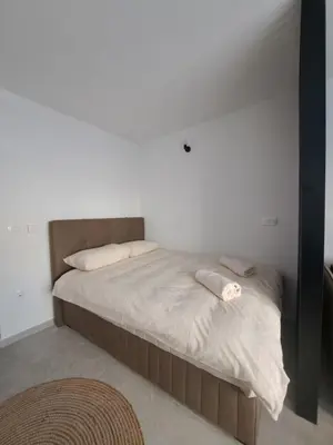 a bed in a bedroom with a white wall at Apartman Lamini in Livno