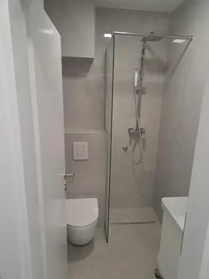 a white bathroom with a shower and a toilet at Apartman Lamini in Livno