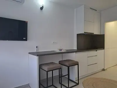 a kitchen with two bar stools and a tv at Apartman Lamini in Livno