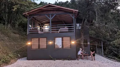 two people sitting at a table in a tiny house at Vila N&M in Visoko