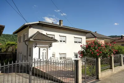 a white house with a fence in front of it at Apartman ATLAS in Jajce