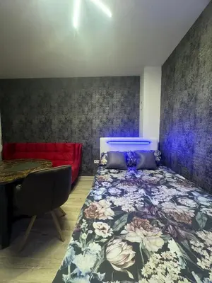 a bedroom with a bed and a red couch at Apartman CITY CENTER 5 in Prijedor