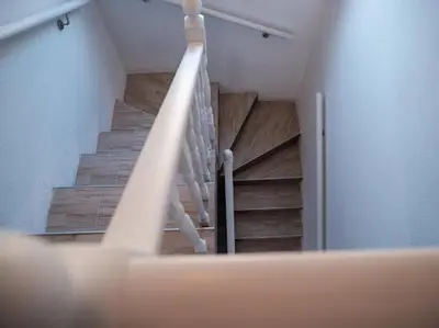 a staircase in a building with wooden floors and white railing at Kuća za odmor -Megy- in Kupres