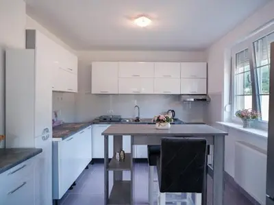 a kitchen with white cabinets and a table in it at Kuća za odmor -Megy- in Kupres