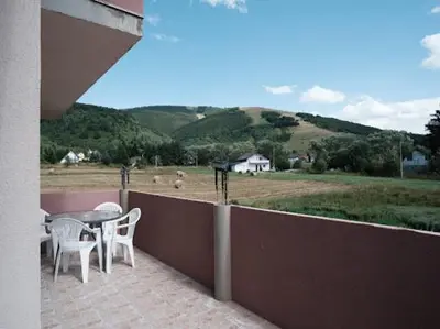 a balcony with a table and chairs and a view of a field at Kuća za odmor -Megy- in Kupres