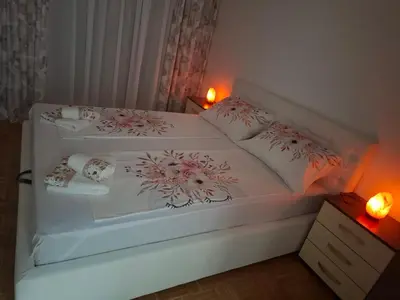a bedroom with a white bed with flowers on it at Apartman Atina Doboj in Doboj
