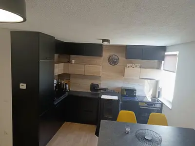 a kitchen with black cabinets and a table with yellow chairs at Apartman Mia Kupres in Kupres