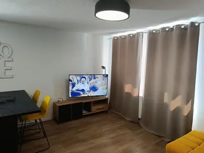 a living room with a flat screen tv and curtains at Apartman Mia Kupres in Kupres