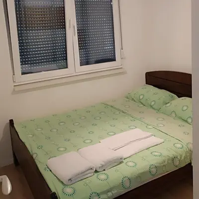 a bed with green sheets and white towels on it at Exclusive Kiseljak apartman in Kiseljak