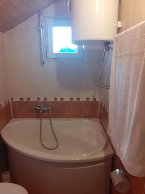a bathroom with a tub and a toilet and a window at OZIM oaza zelenila i mira in Podrašnica