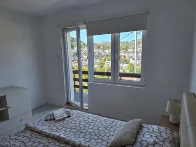 a bedroom with a bed and a large window at Apartman Look in Jajce