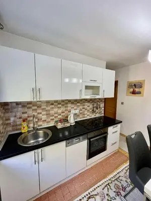 a kitchen with white cabinets and a sink at Garden House in Tuzla