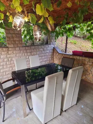 a dining table and chairs with a stone wall at Garden House in Tuzla