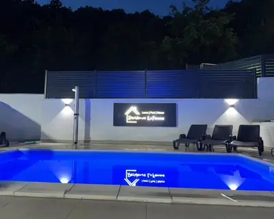 a swimming pool at night with chairs around it at Residence La Femme in Tuzla
