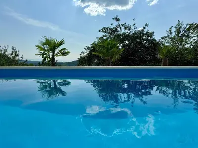 a pool of blue water with trees in the background at Residence La Femme in Tuzla