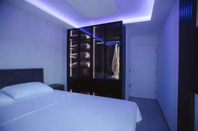 a bedroom with a white bed and a black cabinet at Lux Apartmani Teslić in Teslić