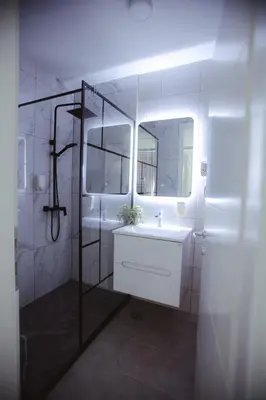 a white bathroom with a sink and a mirror at Lux Apartmani Teslić in Teslić