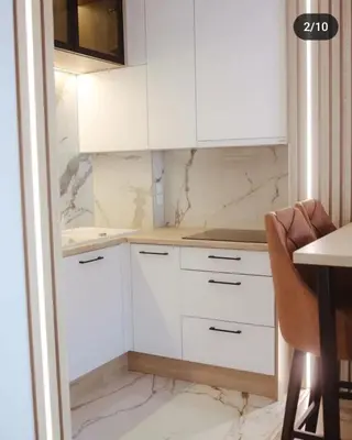 a kitchen with white cabinets and a table at Lux Apartmani Teslić in Teslić