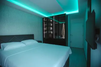 a bedroom with a white bed with a blue light at Lux Apartmani Teslić in Teslić