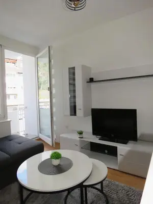 a living room with a table and a tv at Apartman City in Jajce