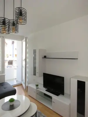 a white living room with a flat screen tv at Apartman City in Jajce