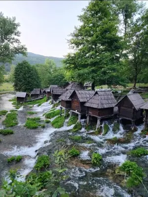 a group of wooden huts in a river at Apartman City in Jajce