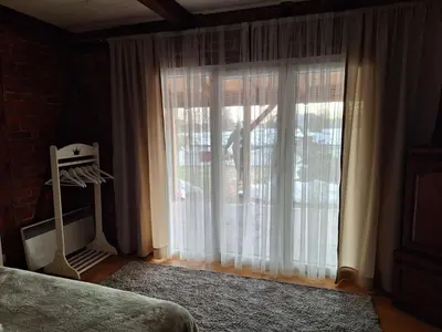 a bedroom with a large window with white curtains at Lake house in Donji Žabar