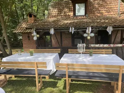 two tables with white table cloths on them in front of a house at Lake house in Donji Žabar