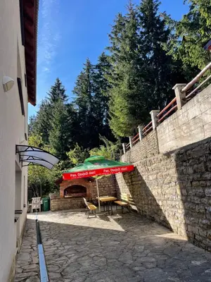 a stone wall with a table and an umbrella at Montis Vlasic Apartment 2 in Vlasic