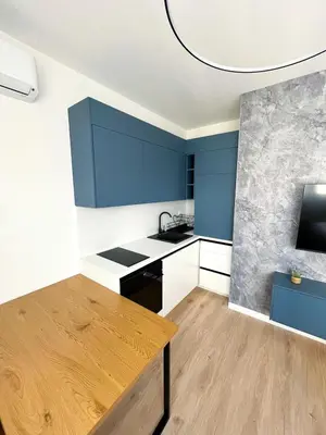 a kitchen with blue cabinets and a wooden table at Apartman Skyroom in Banja Luka