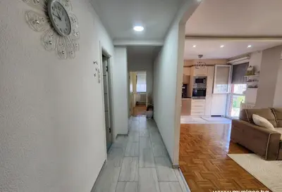 a hallway with a clock on a white wall at Apartman Iris in Tuzla
