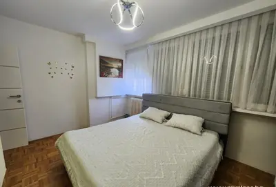 a bedroom with a large bed and a window at Apartman Iris in Tuzla