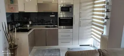 a kitchen with white cabinets and stainless steel appliances at Apartman Iris in Tuzla