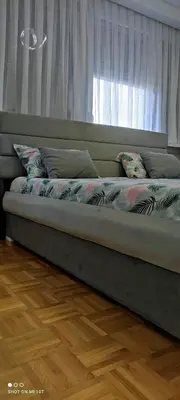 a bed with pillows sitting in a room with a window at Apartman Iris in Tuzla