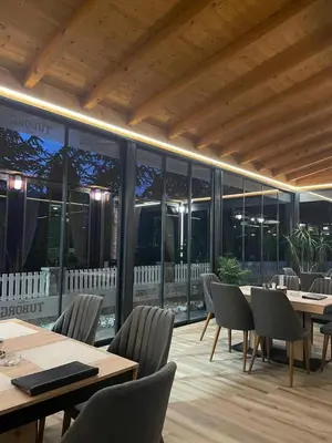 a restaurant with tables and chairs and large windows at Restoran Motel Kanjon in Skender Vakuf