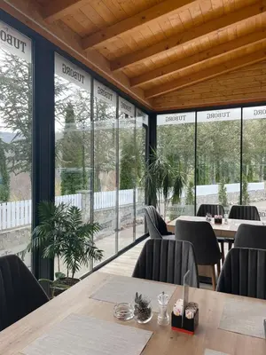 a restaurant with tables and chairs and large windows at Restoran Motel Kanjon in Skender Vakuf