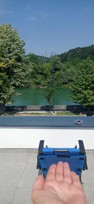 a hand holding a blue object in front of a view at Apartman Una na dlanu, Novi Grad in Bosanski Novi