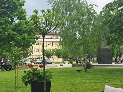 a park with trees and a building in the background at Real Dream in Prijedor