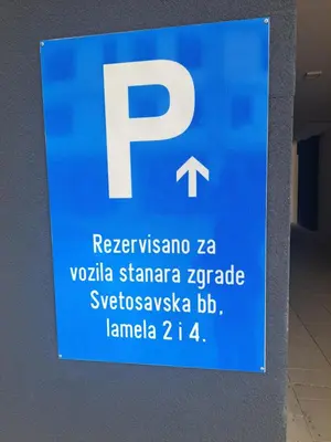 a blue parking sign on the side of a wall at Real Dream in Prijedor