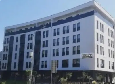a large white building with a blue stripe on it at Real Dream in Prijedor