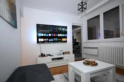 a living room with a table and a tv on the wall at Apartman Lamela in Zenica