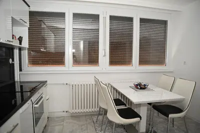 a white kitchen with a white table and chairs at Apartman Lamela in Zenica