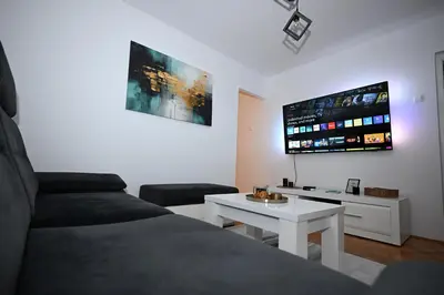 a living room with a bed and a white table at Apartman Lamela in Zenica