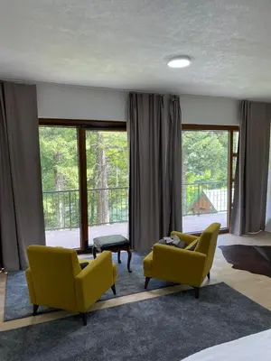 a living room with two chairs and a couch and windows at Villa Bella Una-Apartman in Ostrožac