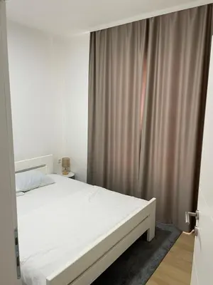 a bedroom with a white bed and a curtain at Villa Bella Una-Apartman in Ostrožac