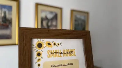 a picture of a sign in a frame with sunflowers at Small House Apartment in Bihać